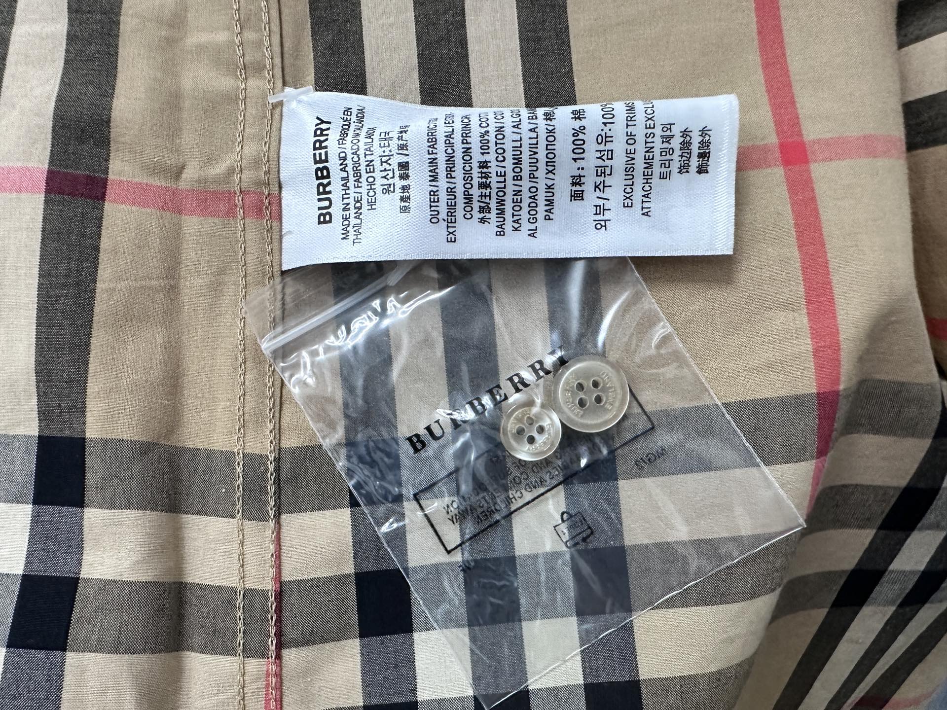 Burberry check shirt with care label and button pack on fabric