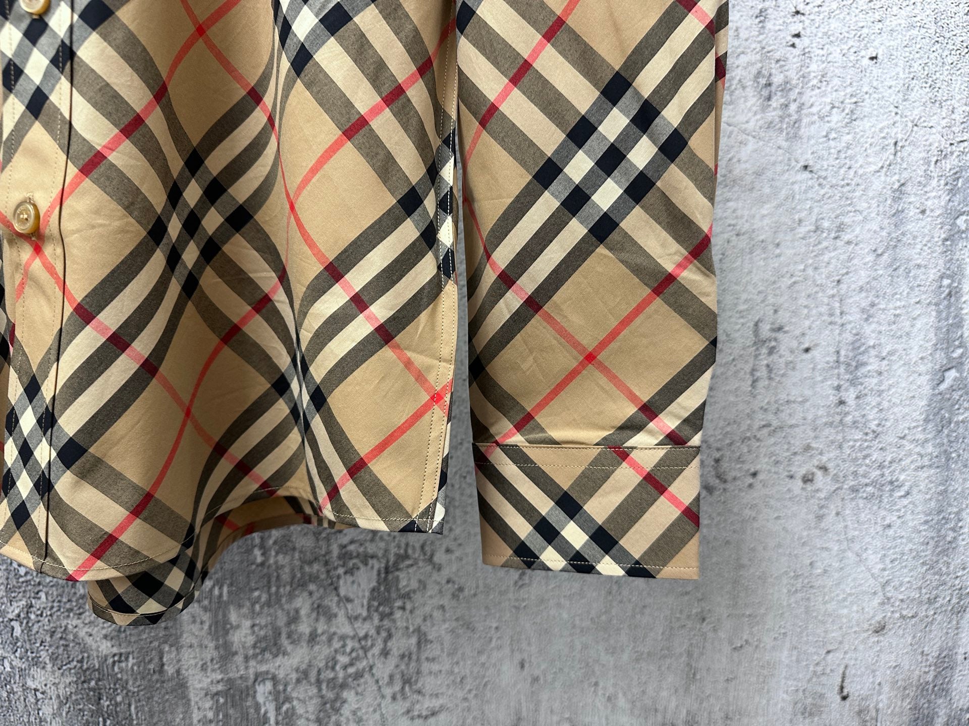 Burberry plaid long-sleeve shirt cuff and hem detail, beige fabric with black and red plaid