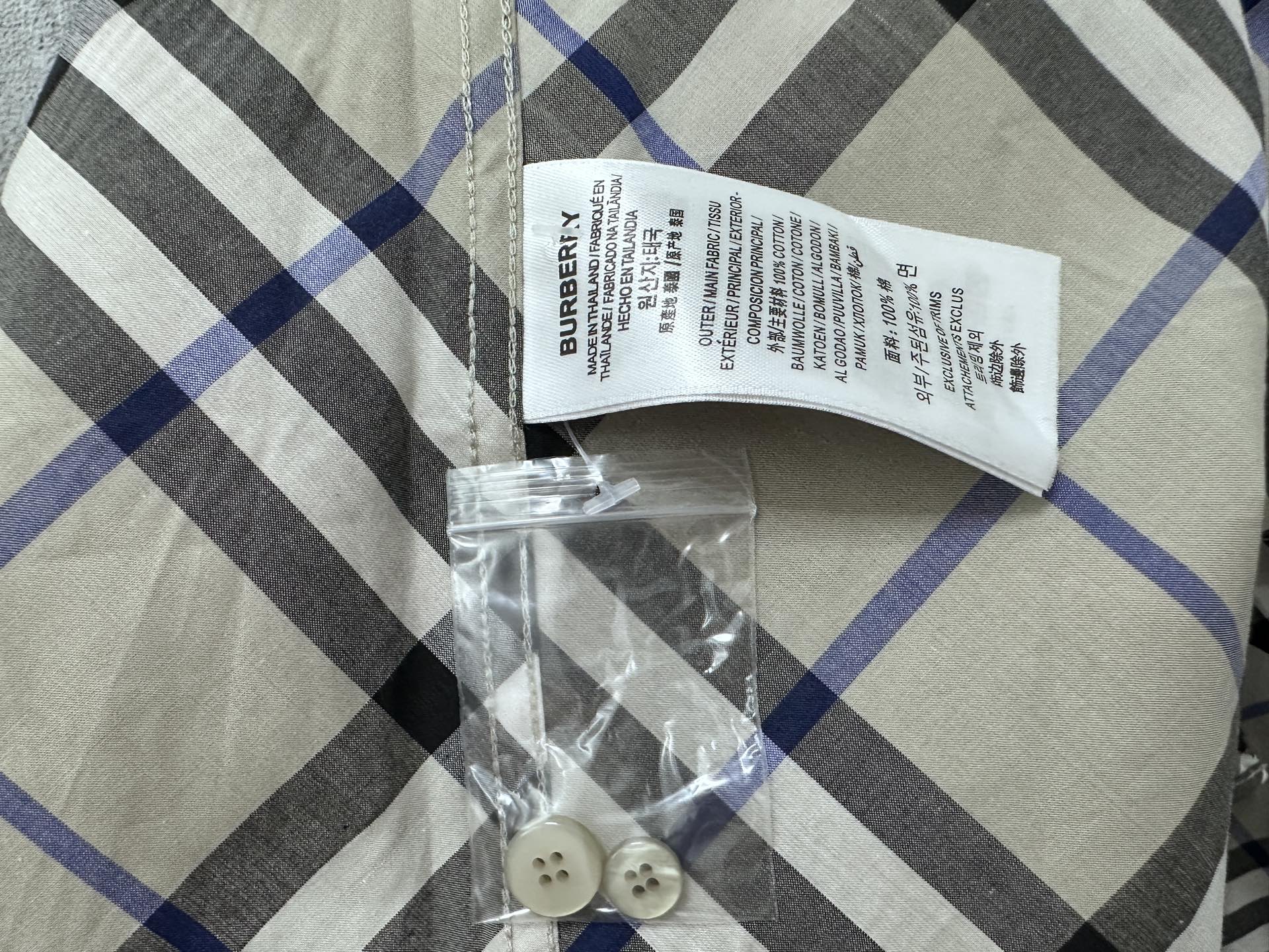Burberry plaid shirt care label and spare buttons; beige, blue, and black check
