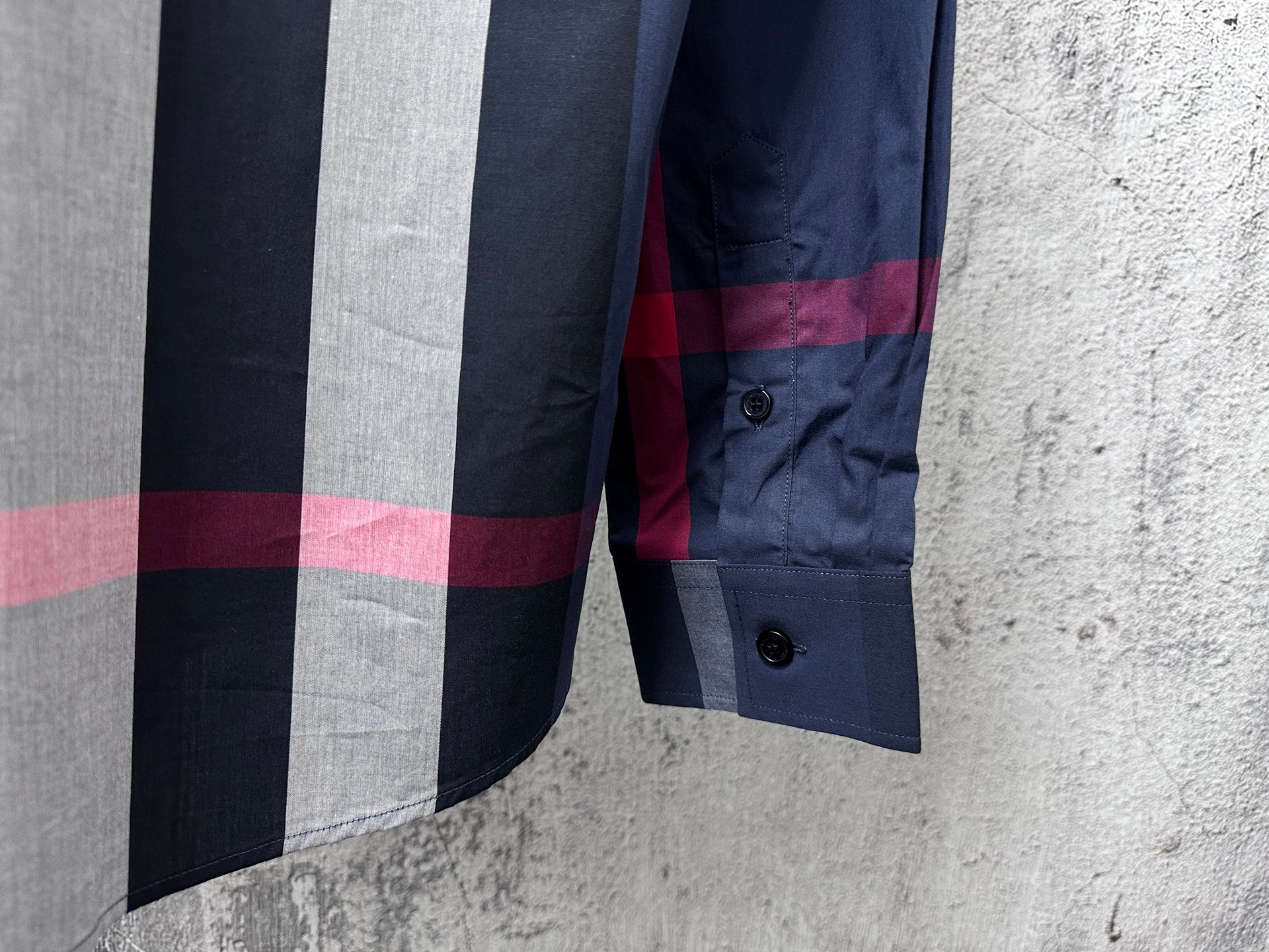 Burberry plaid button-up shirt cuff detail with navy, gray, and red stripes