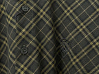 Close-up of plaid shirt front with dark buttons and embroidered emblem