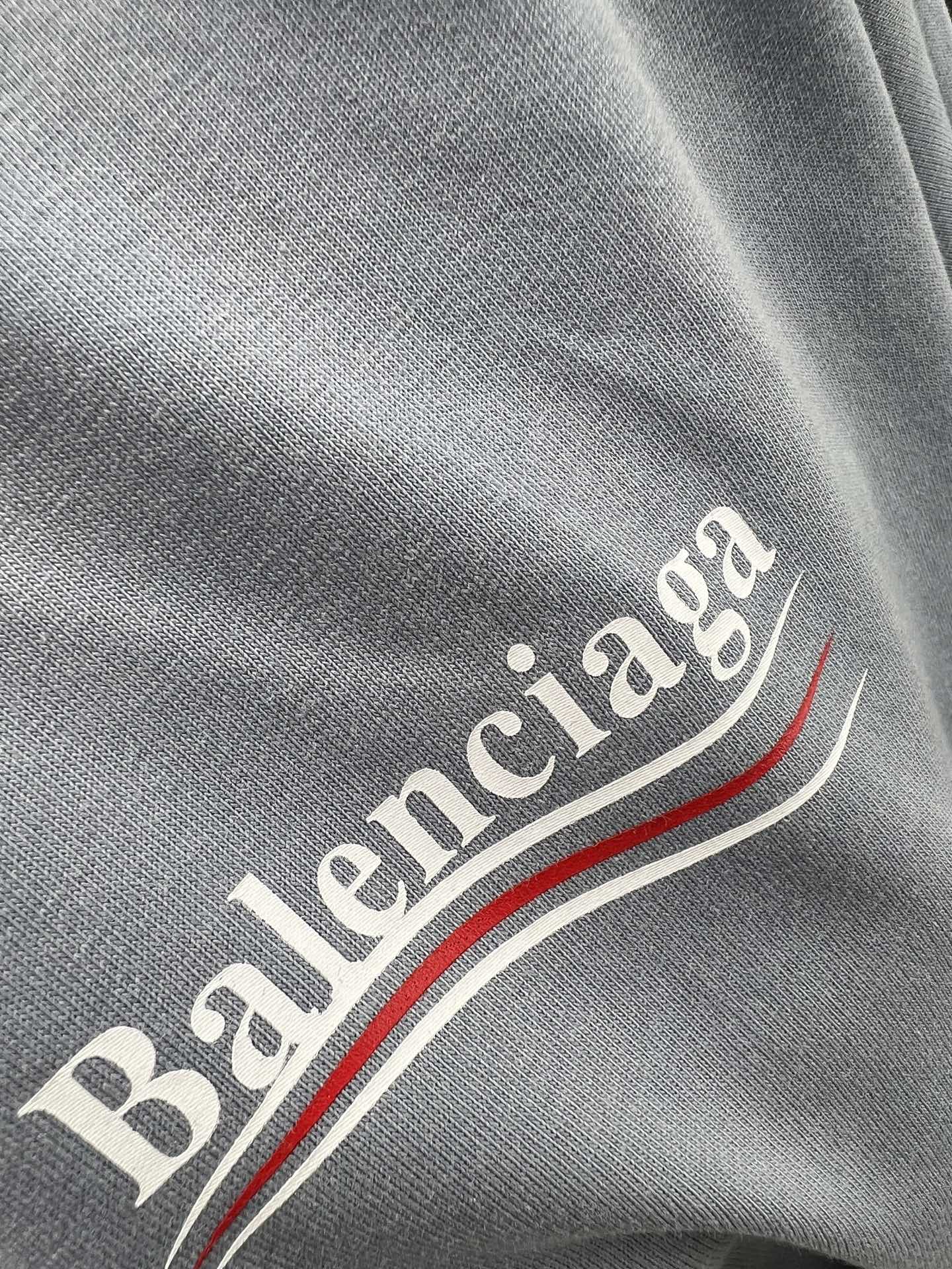 Gray fabric close-up with Balenciaga lettering and red-and-white stripe detail.
