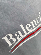 Gray fabric close-up with Balenciaga text and red-and-white stripe detail.