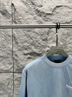 Light blue short-sleeve T-shirt collar with partial Balenciaga logo on the chest.