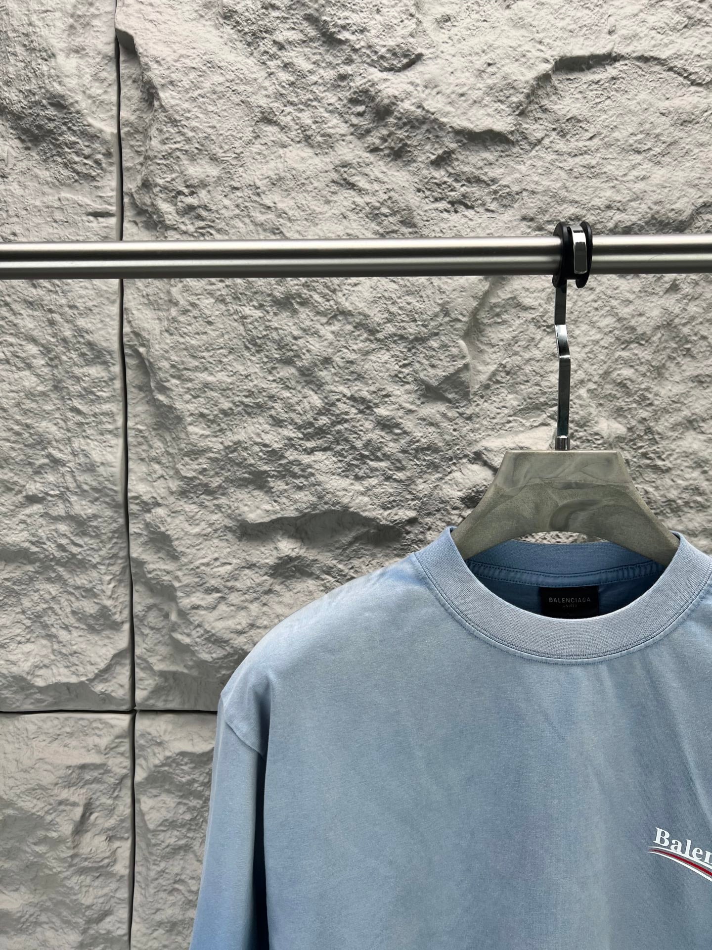 Light blue short-sleeve T-shirt collar with partial Balenciaga logo on the chest.