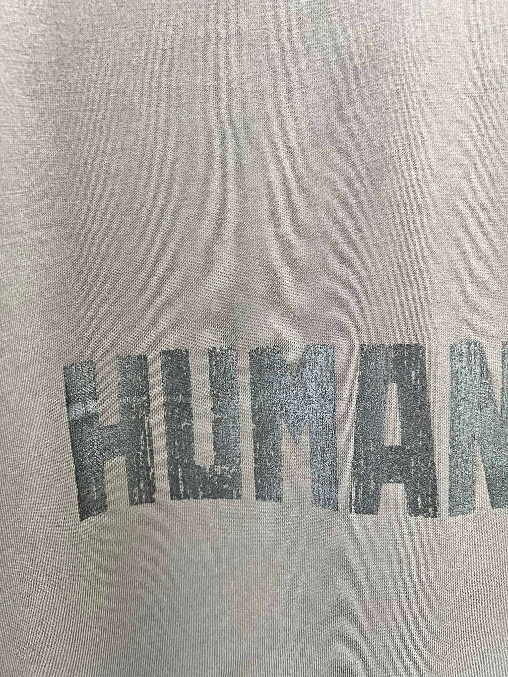 Crew-neck T-shirt fabric with large distressed graphic text print.