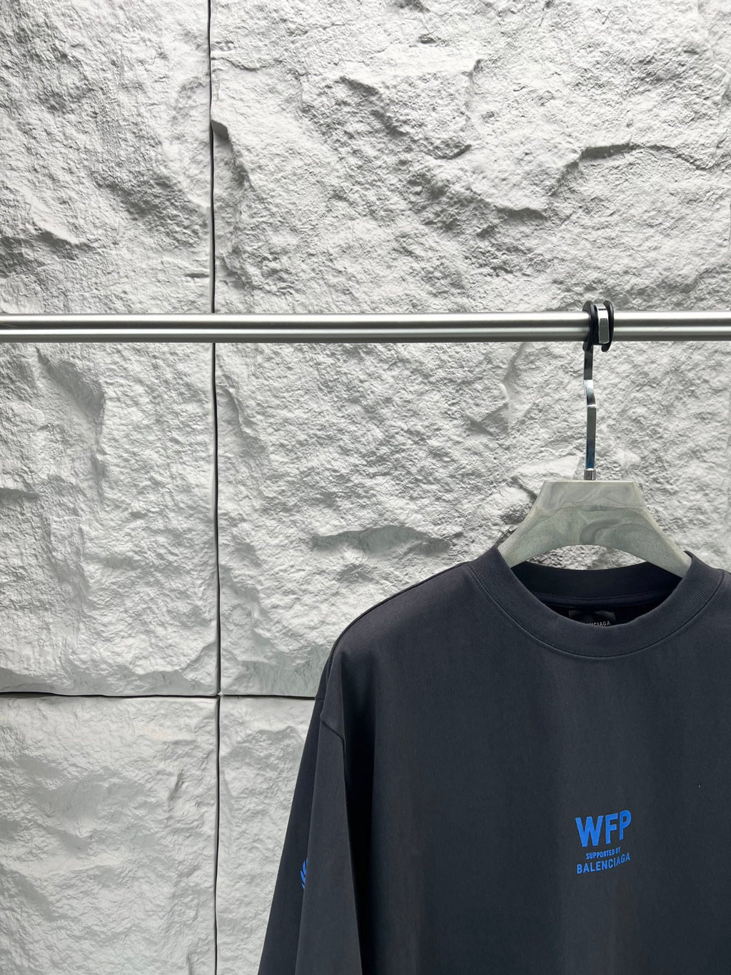 Black short-sleeve T-shirt close-up at chest with small blue WFP Balenciaga logo