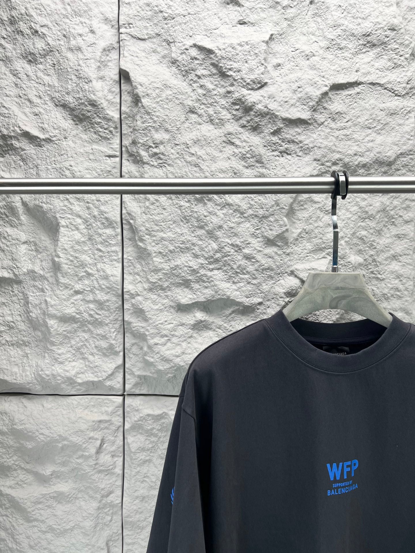 Black short-sleeve T-shirt close-up at chest with small blue WFP Balenciaga logo