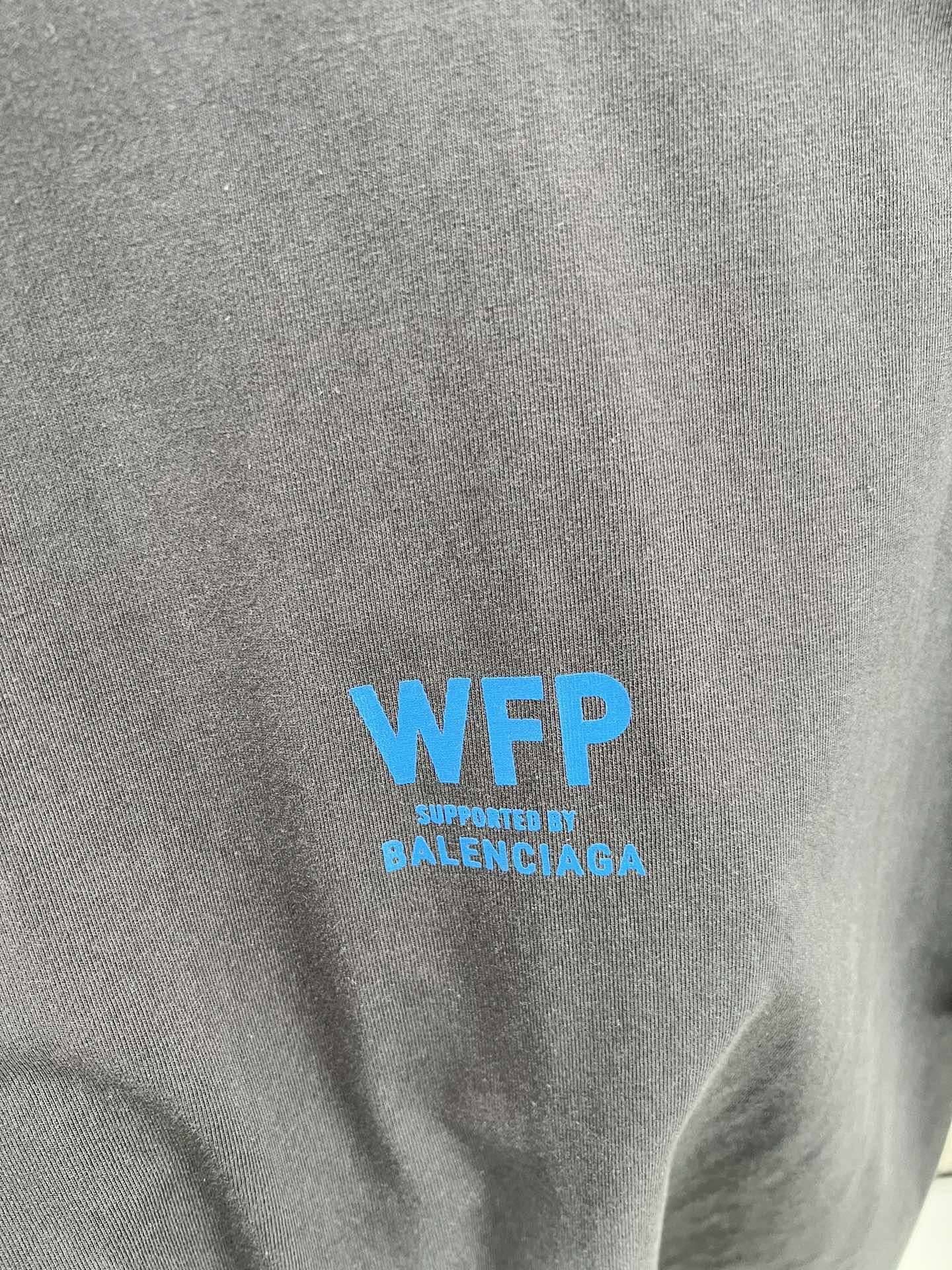 Gray T-shirt chest with blue “WFP” and “Supreme by BALENCIAGA” text