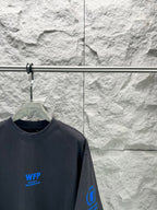 Black short-sleeve T-shirt close-up with blue WFP Balenciaga logo and sleeve print