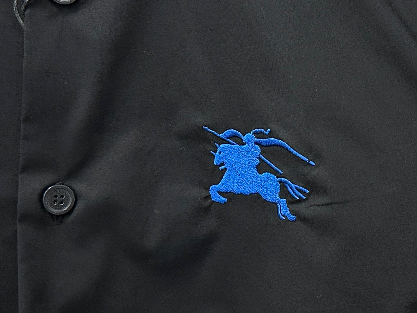 Blue horse logo on Burberry long-sleeve shirt, black fabric with button detail