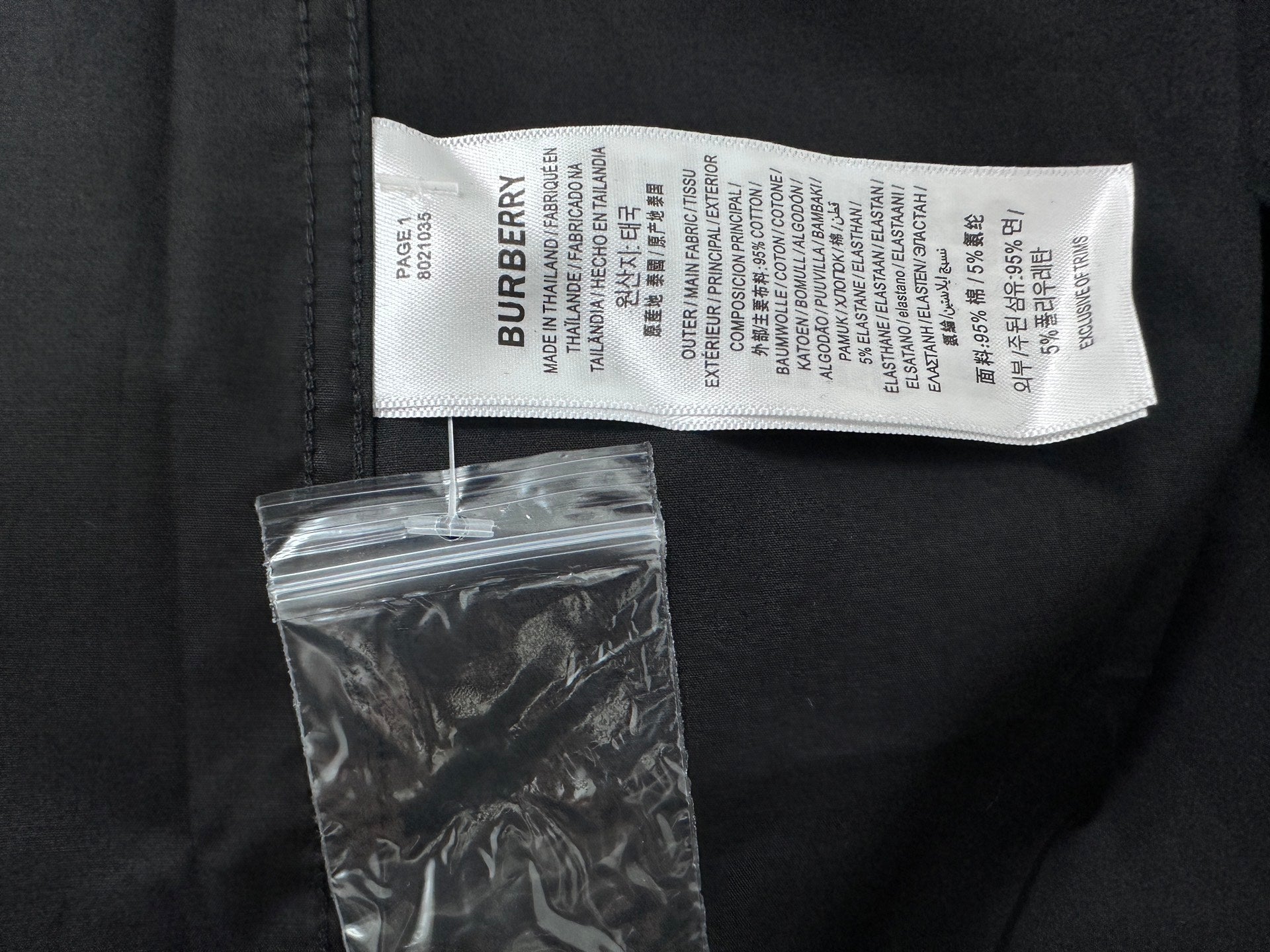 Burberry shirt interior neck label and care tag on black fabric