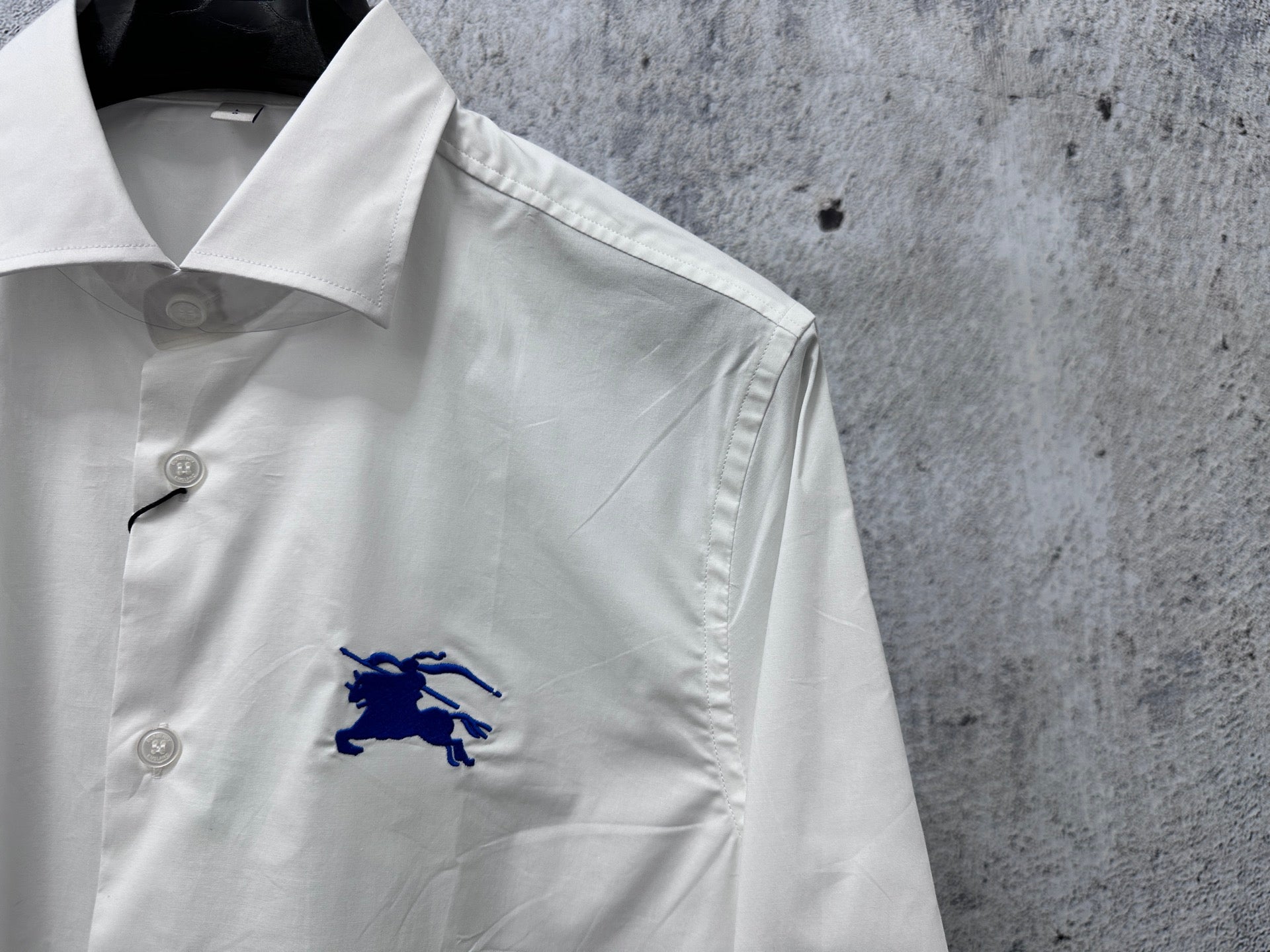 White shirt with embroidered blue horse logo on chest