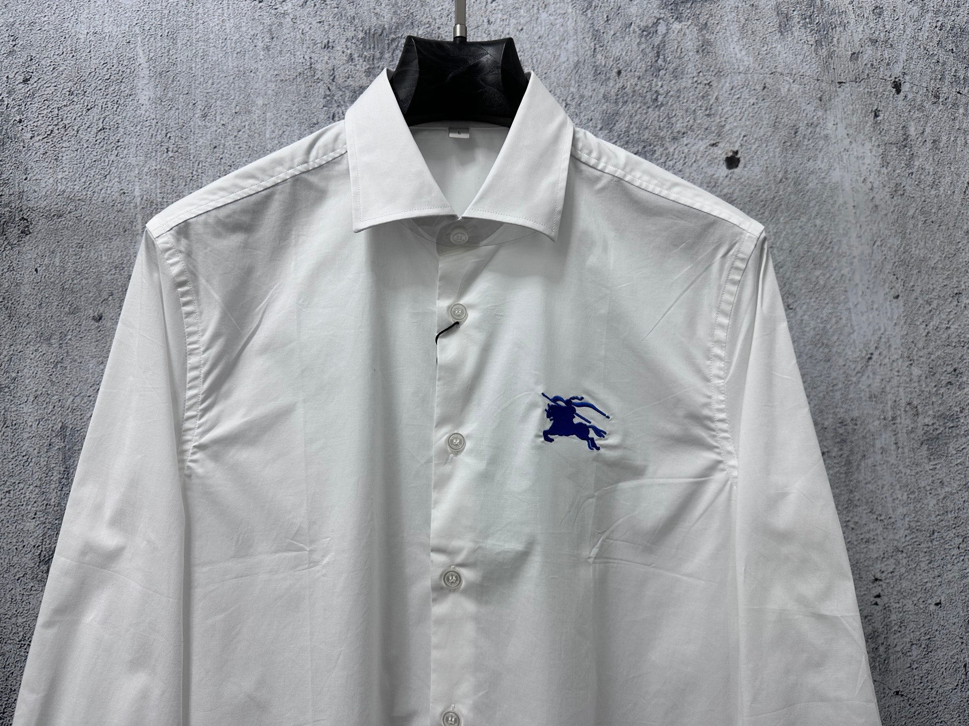 White long-sleeve button-up shirt with blue horse logo and button front