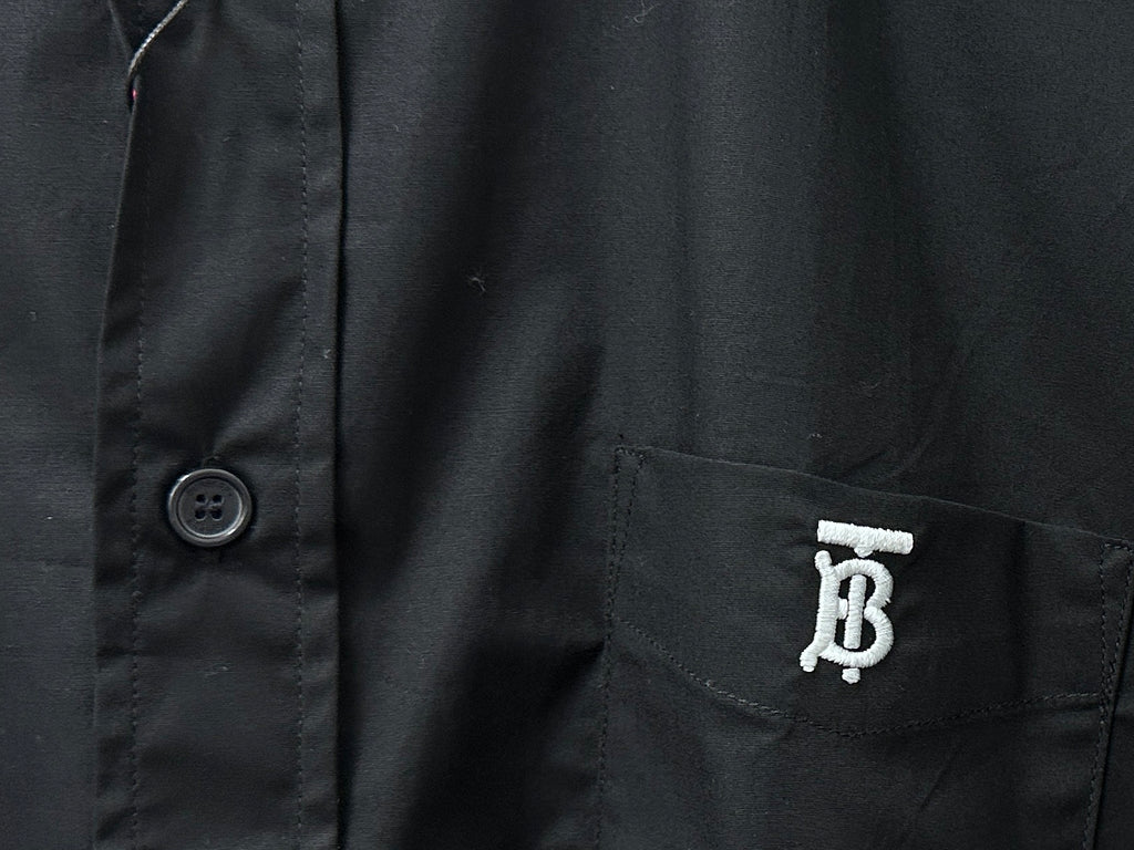 Long-sleeve button-up shirt detail: chest pocket with logo and round button
