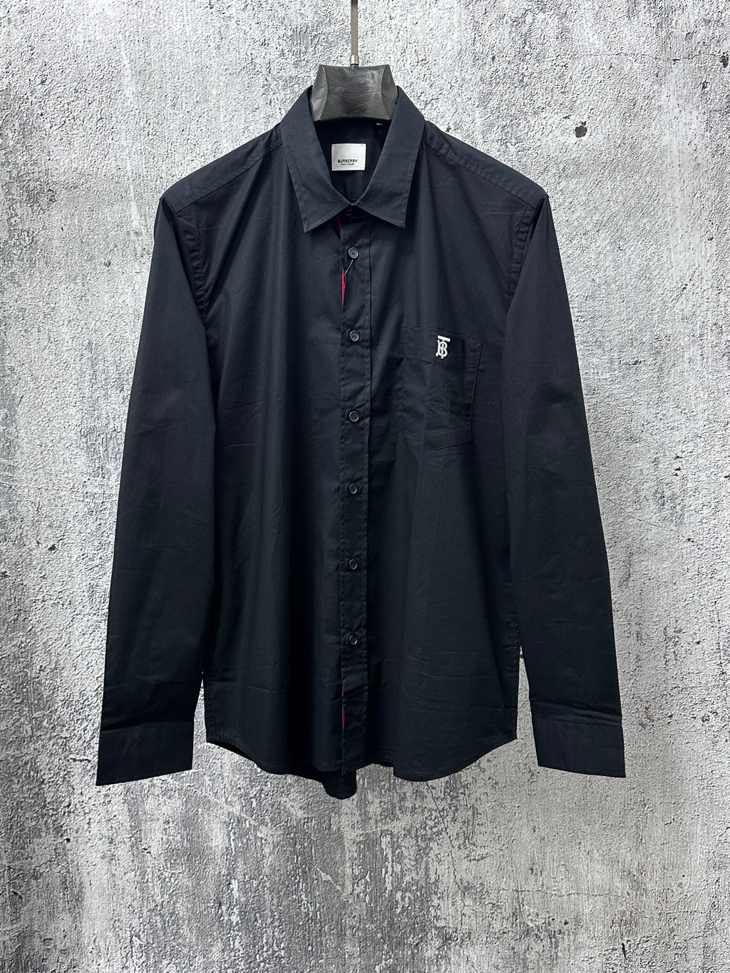 Long-sleeve button-up shirt, dark with pointed collar and chest logo patch