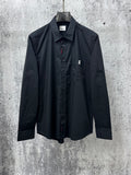 Long-sleeve button-up shirt, dark with pointed collar and chest logo patch