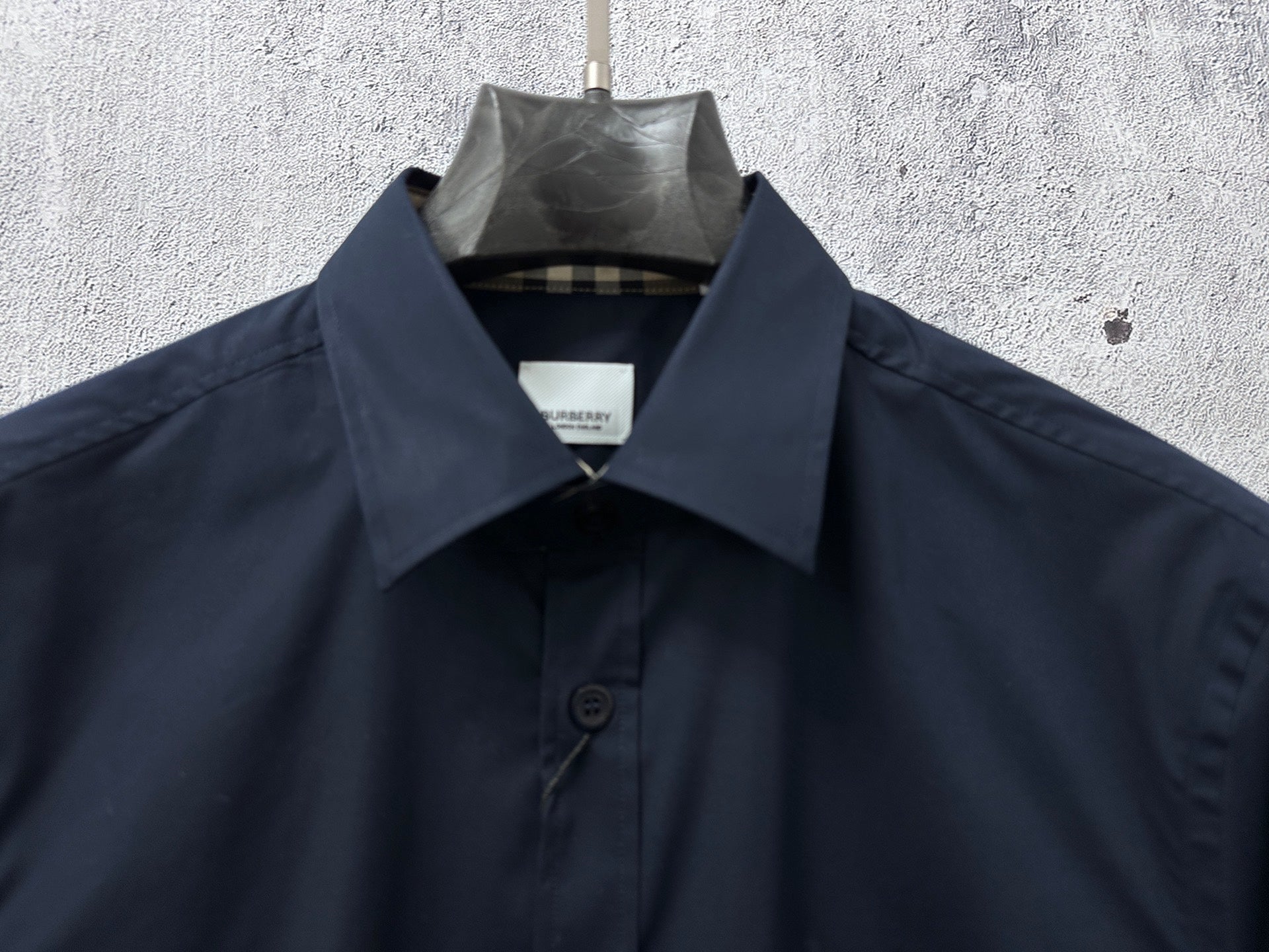 Navy button-up shirt collar with interior check lining and top button
