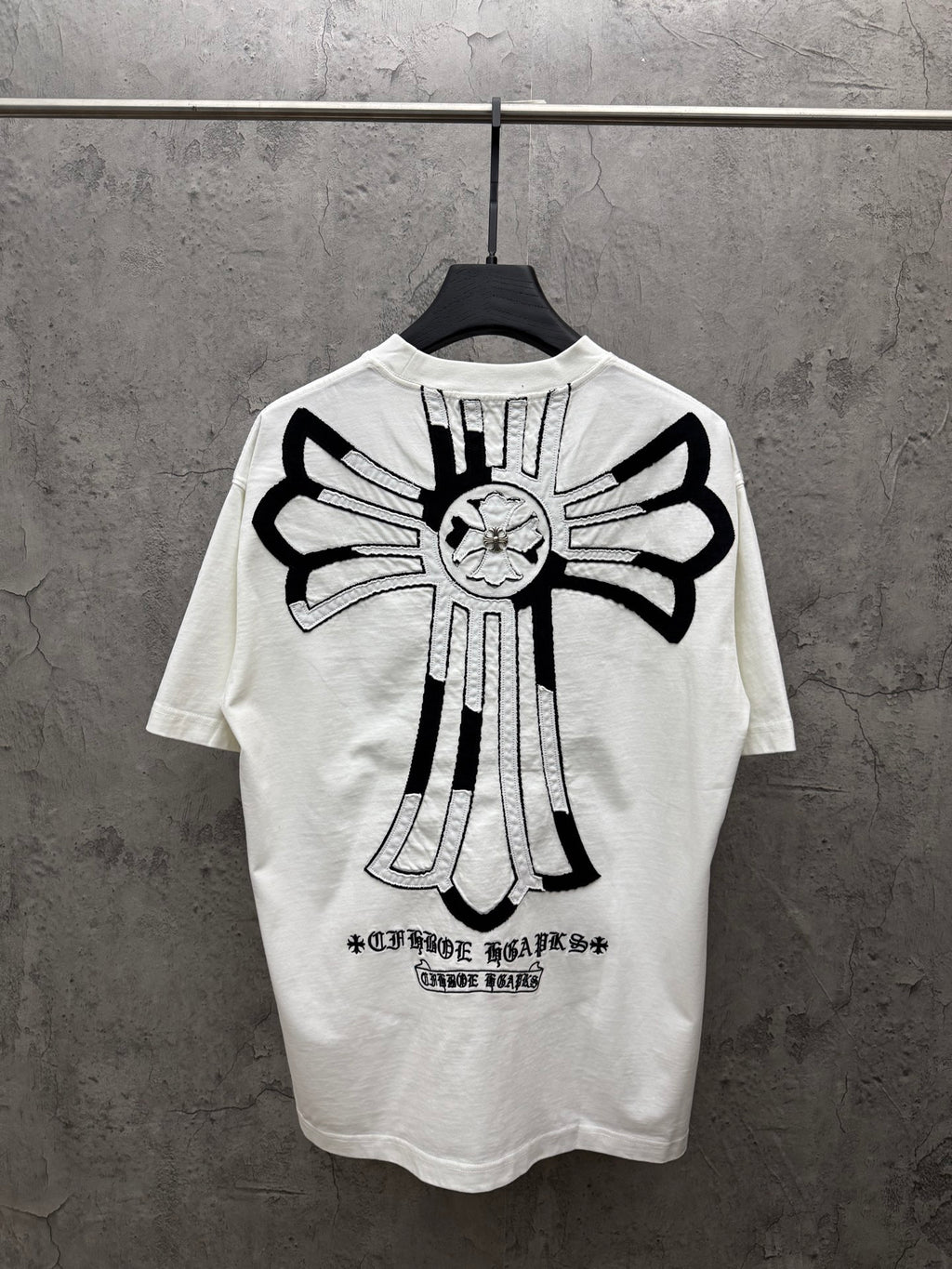 White short-sleeve T-shirt with large black back cross graphic and text