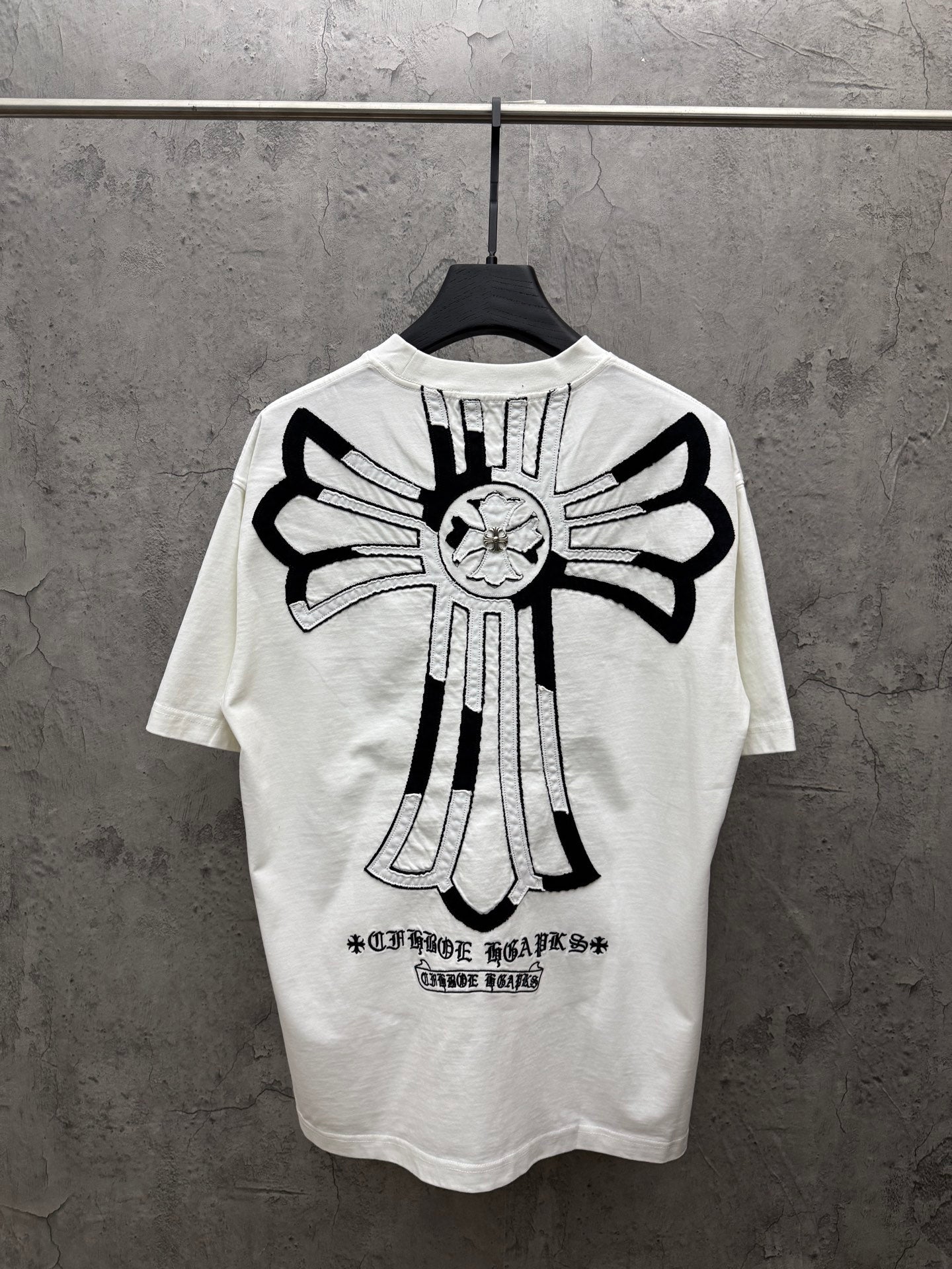 White short-sleeve T-shirt with large black back cross graphic and text