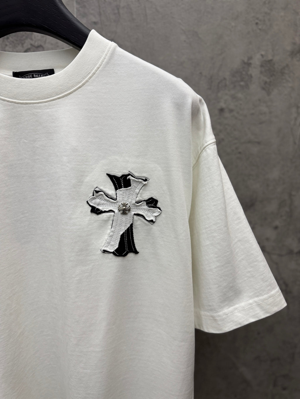 White short-sleeve T-shirt with small embroidered cross graphic on the chest.