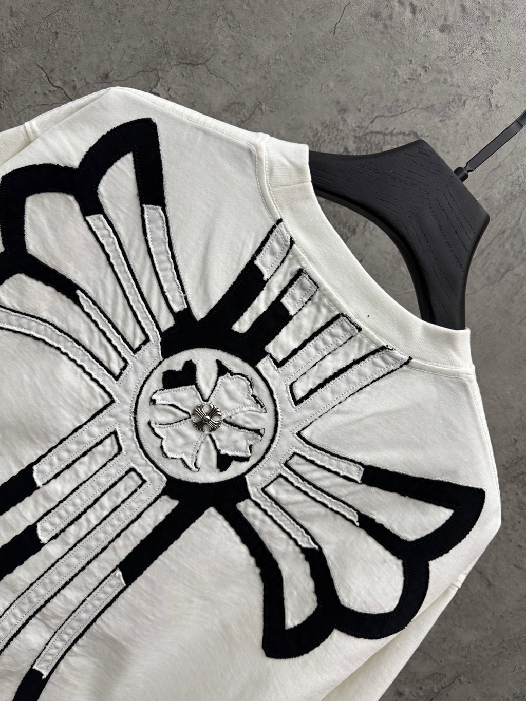 White T-shirt back cross graphic close-up with black outlines and silver detailing