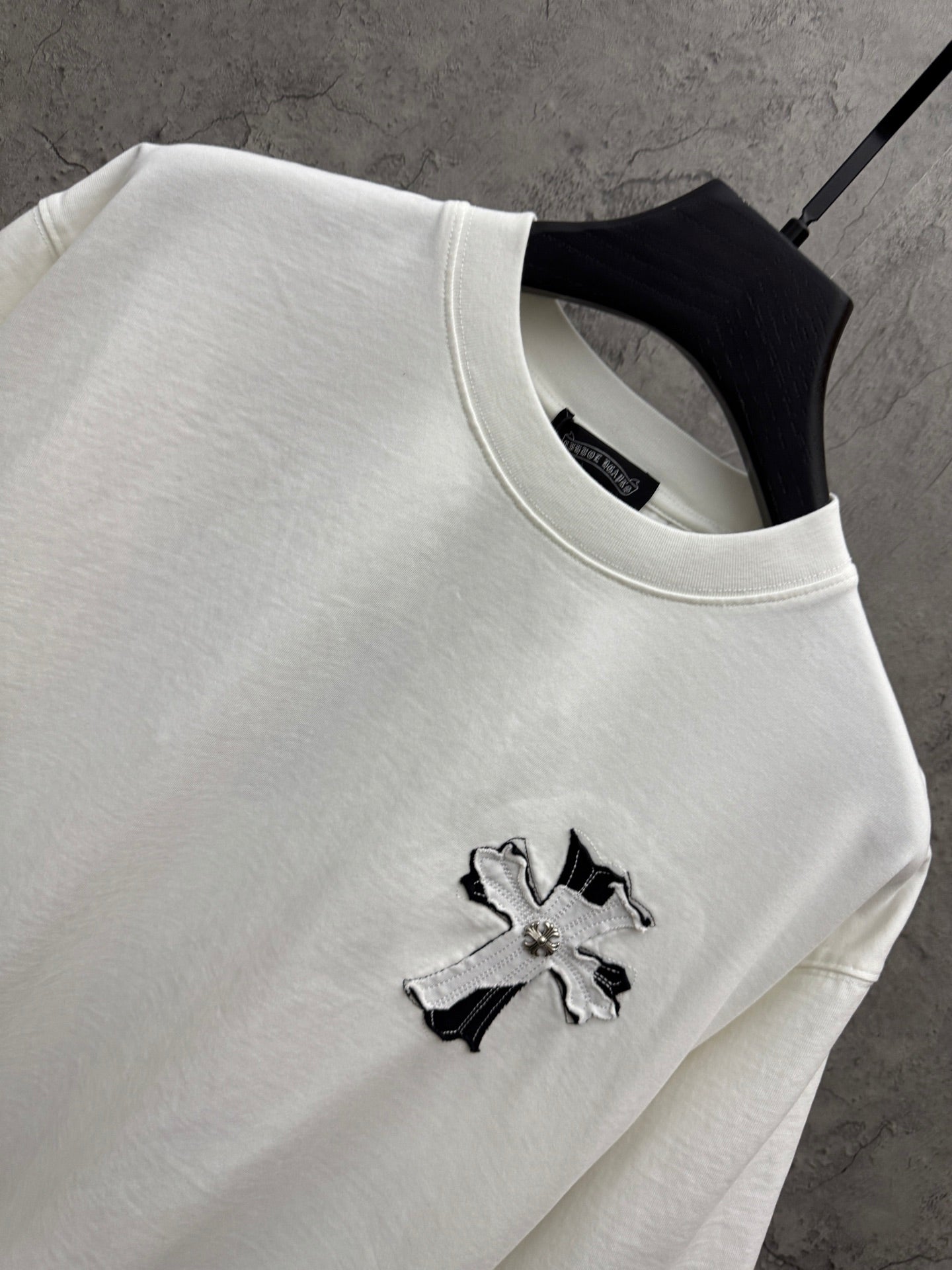 White short-sleeve T-shirt neckline detail with small cross graphic