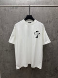 White short-sleeve T-shirt with small black-and-silver cross graphic on chest