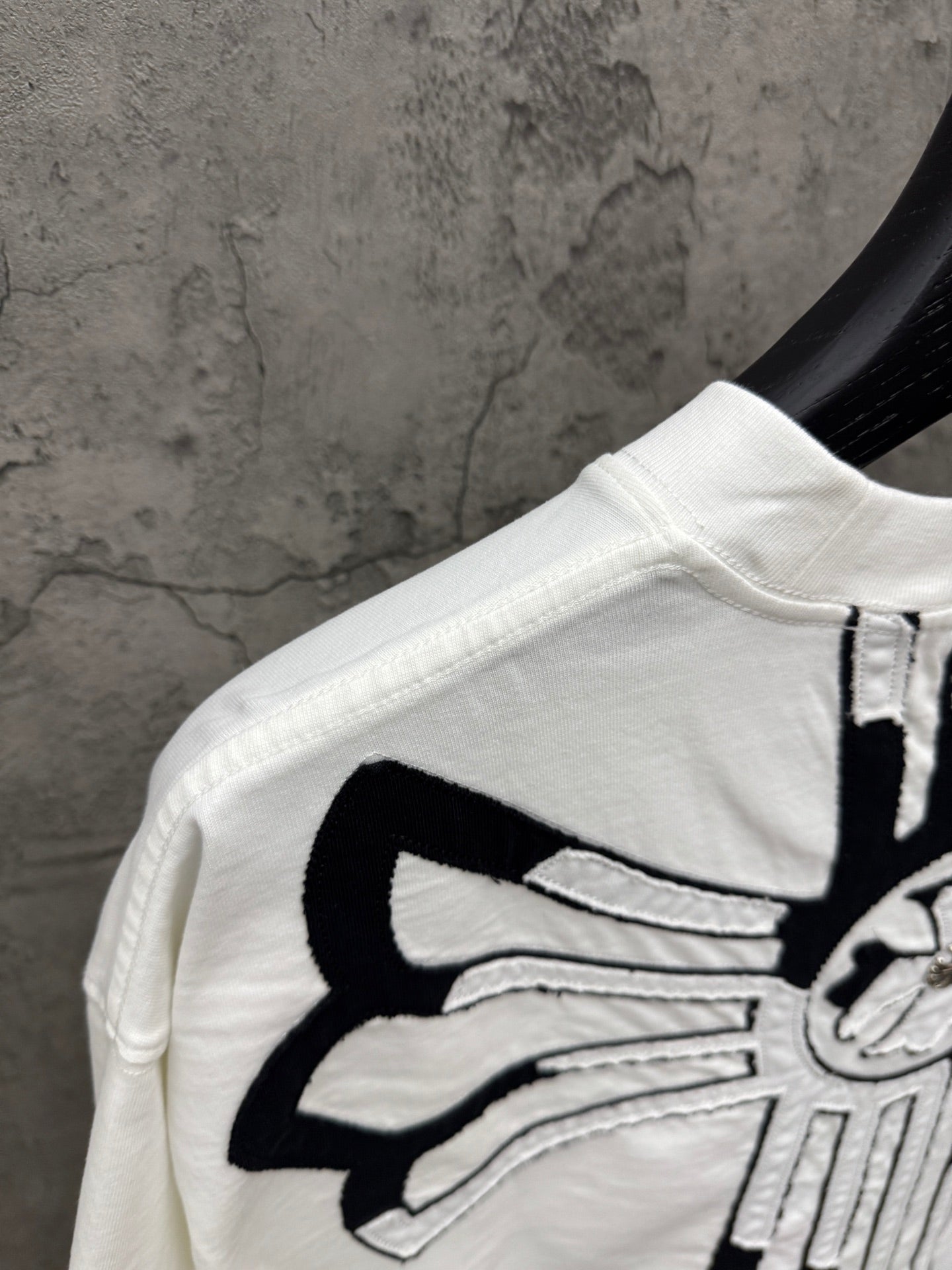 White T-shirt shoulder and sleeve with large black crossburst graphic detail