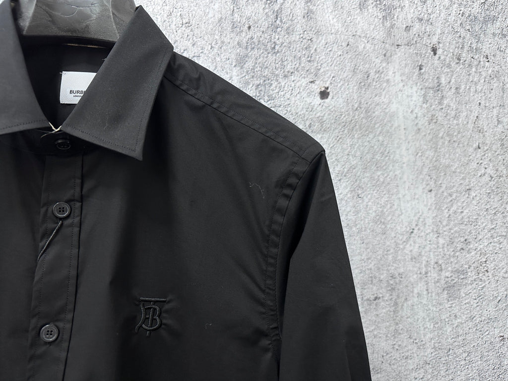 Black button-up shirt with left chest button detail and short embroidered emblem