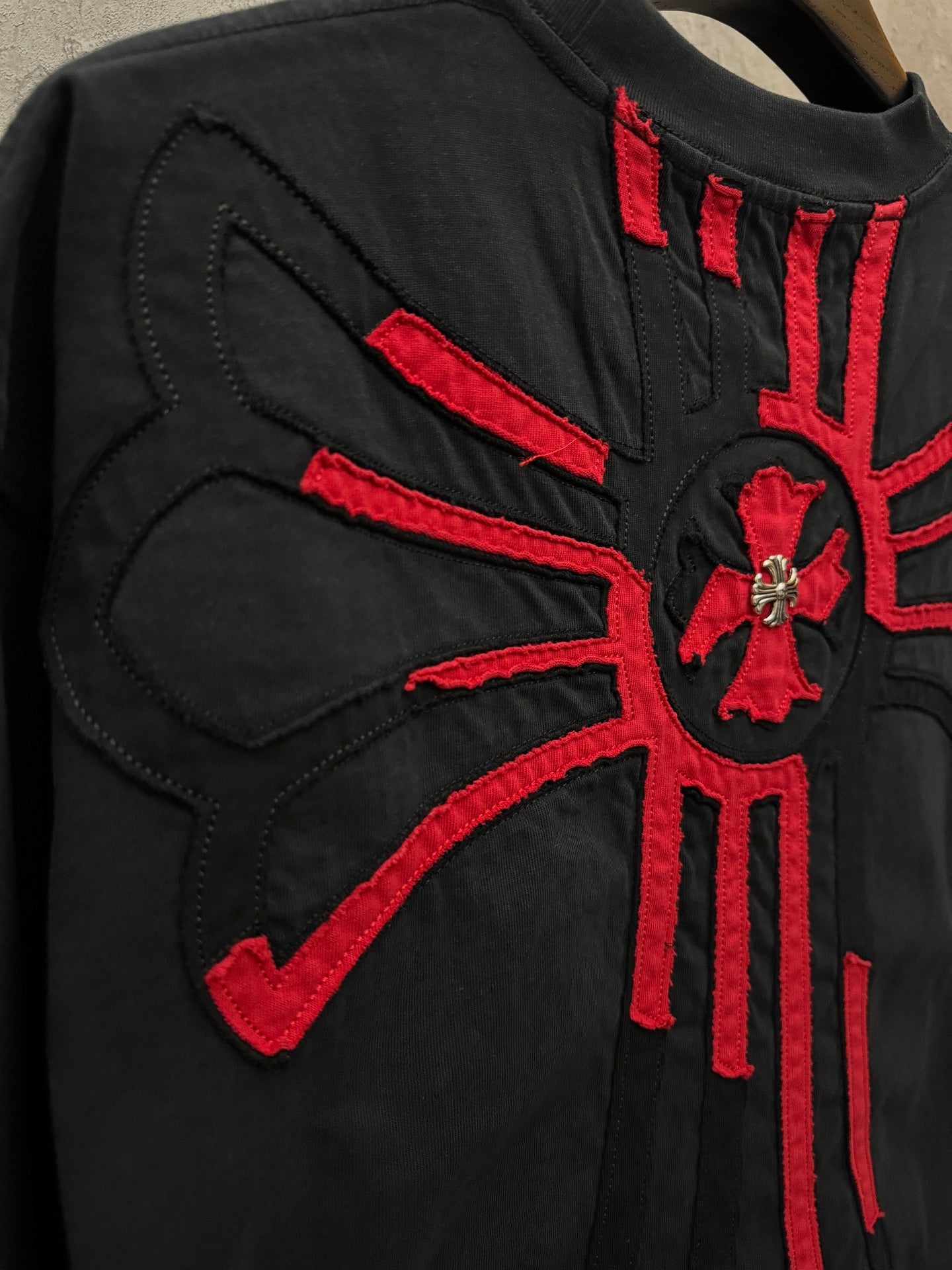 Black T-shirt back with red radial cross embroidery and stitch detail