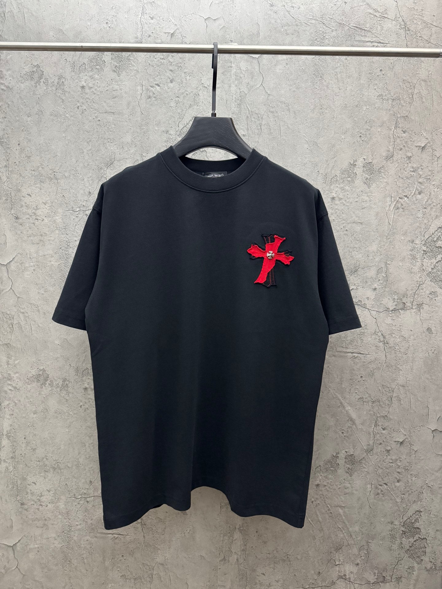 Black short-sleeve T-shirt with small red cross emblem on chest