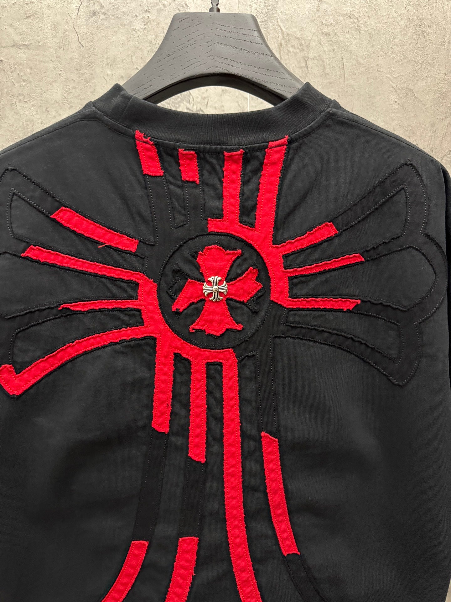 Black T-shirt back with large red radial cross graphic and applique