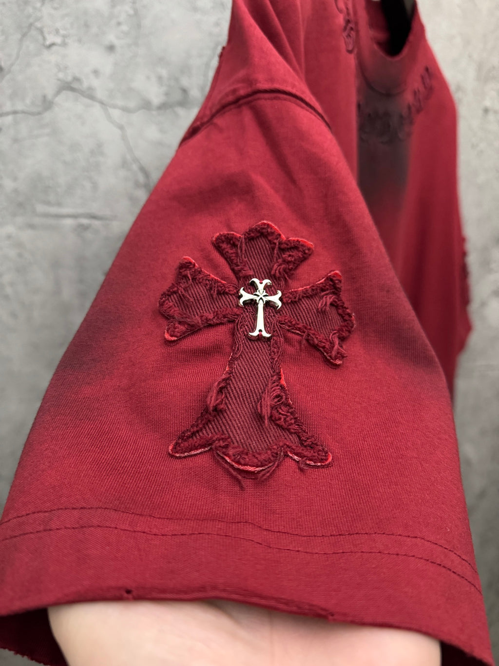 Red T-shirt sleeve with embroidered cross emblem at shoulder