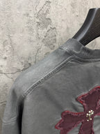 Grey T-shirt side view with maroon cross applique and double-needle hem stitching