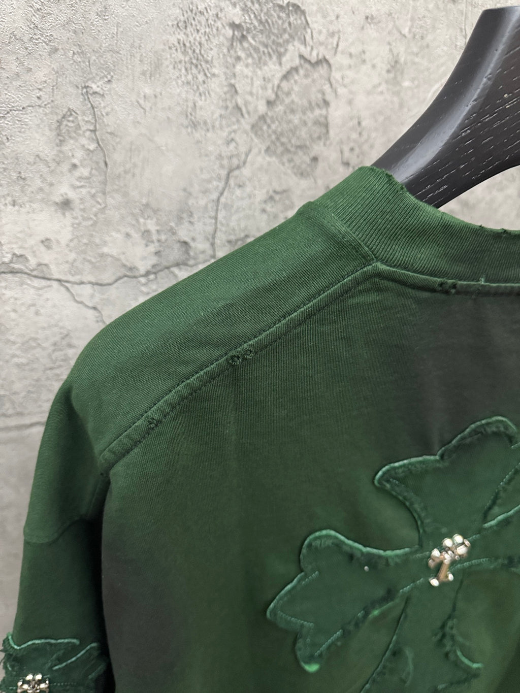 Green short-sleeve T-shirt close-up of shoulder with embroidered angel cross patch