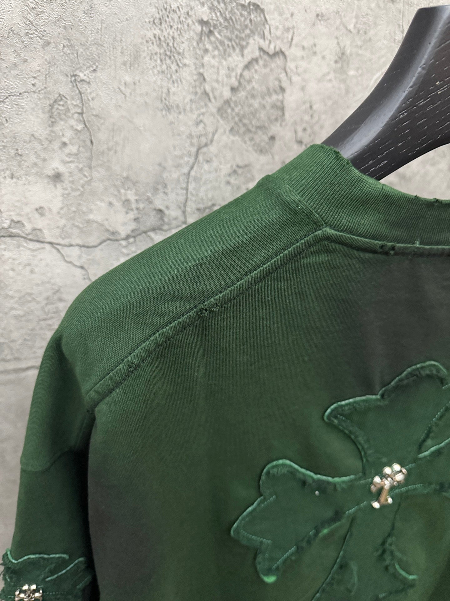 Green T-shirt with embroidered cross detail on the shoulder