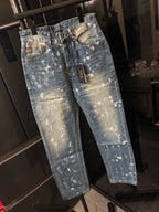 Distressed light-wash denim jeans with white splatter, angled front view