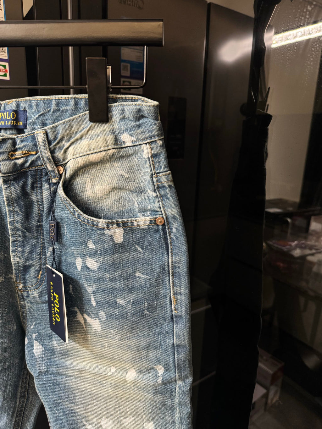Distressed light-wash denim jeans with white speckle splatter, front pocket view