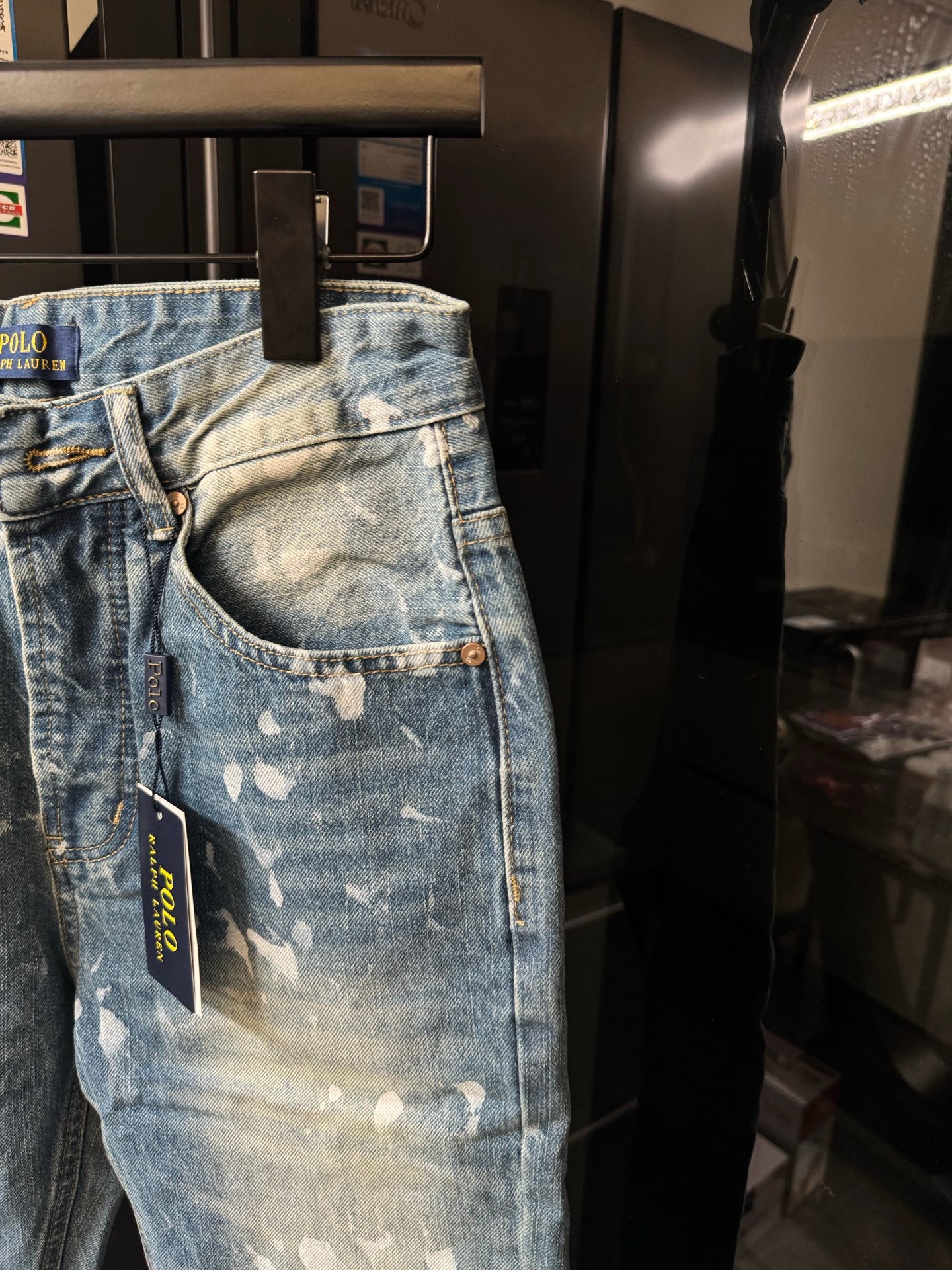 Distressed light-wash denim jeans with white speckle splatter, front pocket view