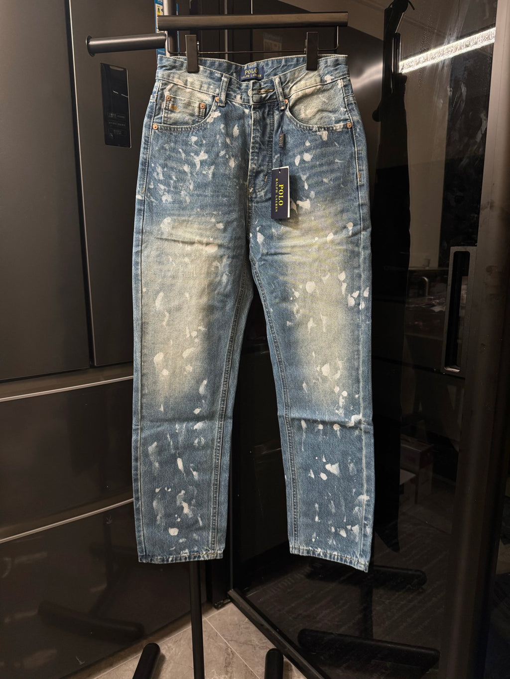 Distressed light-wash denim jeans with white speckle splatter, front view