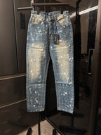 Distressed light-wash denim jeans with white speckle splatter, front view