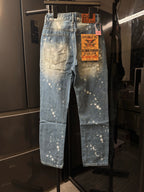 Distressed light-wash denim jeans with white speckle splatter and brand tag