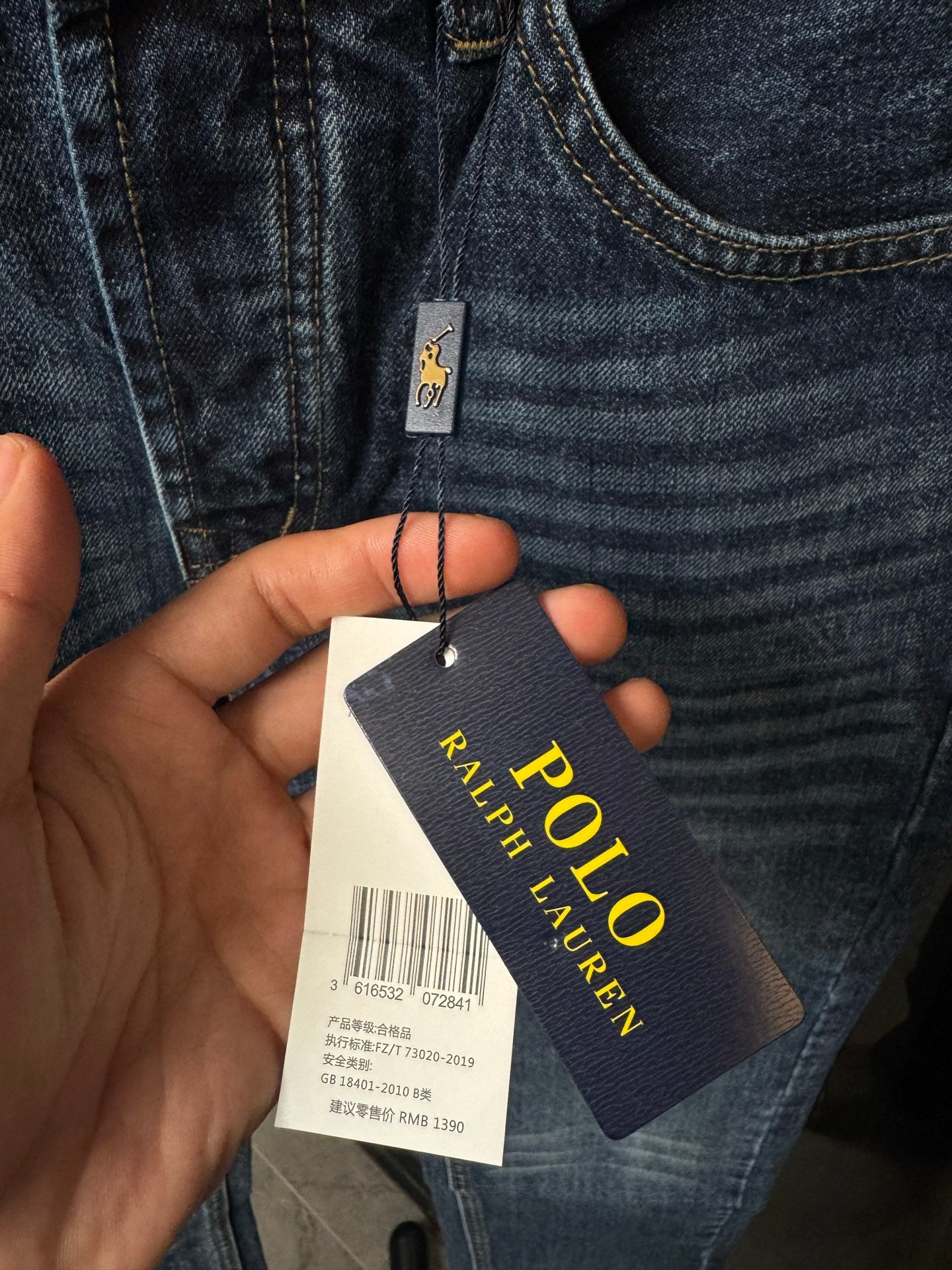 Denim jeans with attached POLO Ralph Lauren hang tag held in a hand