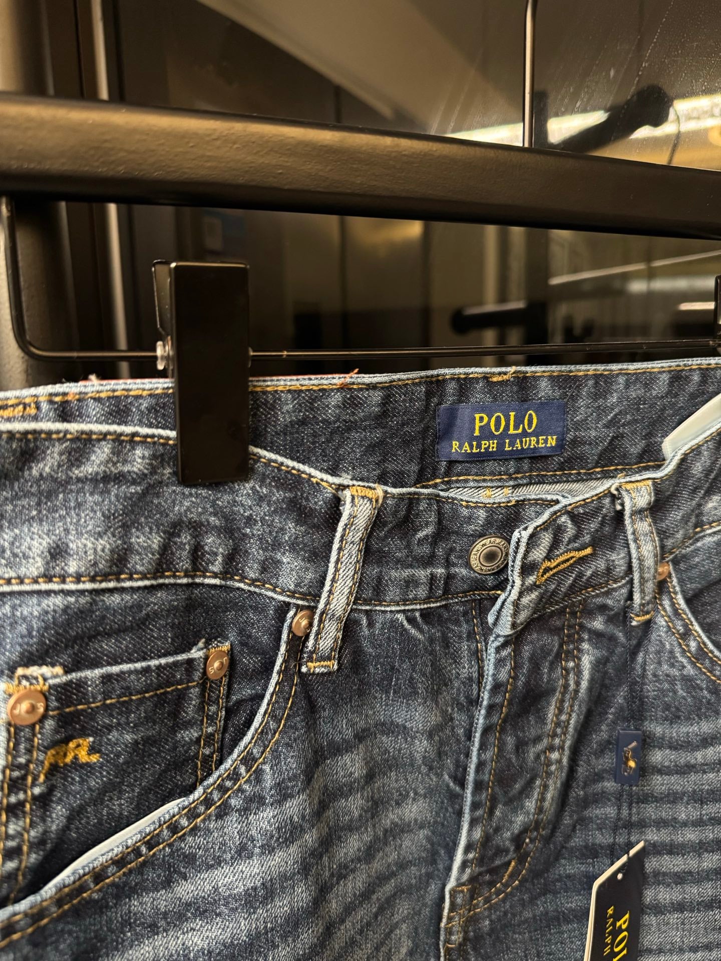 Close-up of light blue denim jeans waistband with POLO Ralph Lauren label and button