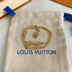 Gold-tone charm bracelet on beige pouch with blue ribbon, Louis Vuitton logo