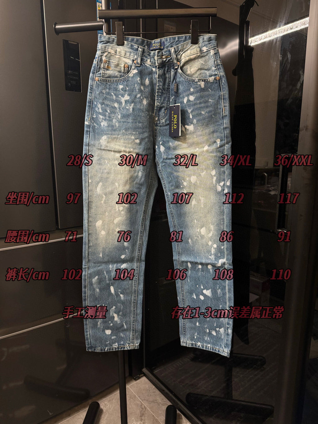 Distressed light-wash denim jeans with white speckle splatter, hanging front view