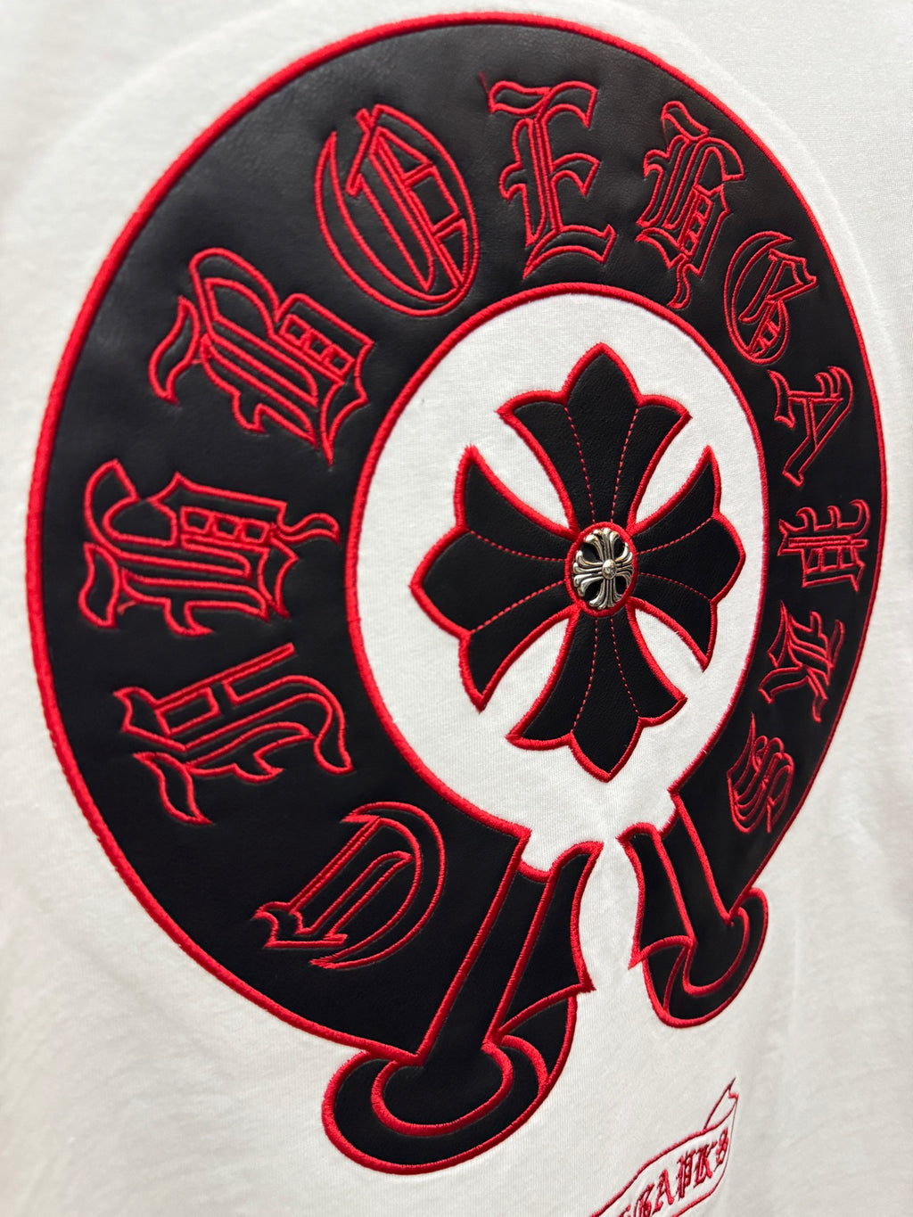Close-up of red-and-black circular graphic on white T-shirt with cross emblem