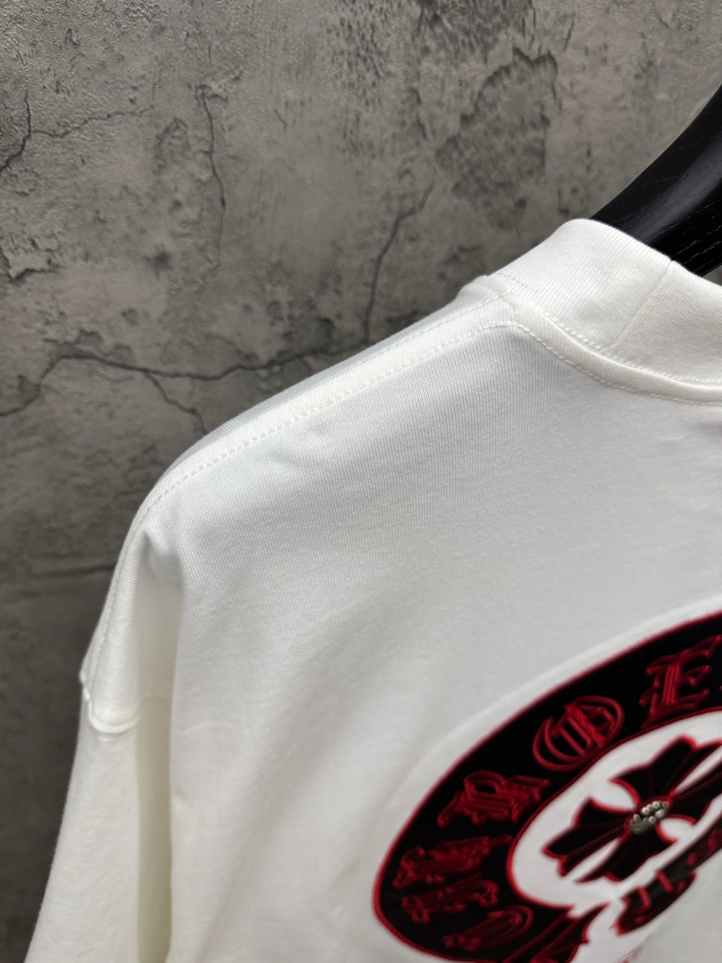 White T-shirt shoulder and collar with partial red-and-black circular logo