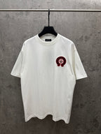 White crew-neck T-shirt with red and black circular logo on left chest